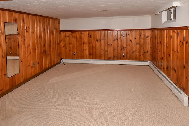 basement with baseboard heating, wood walls, and light carpet