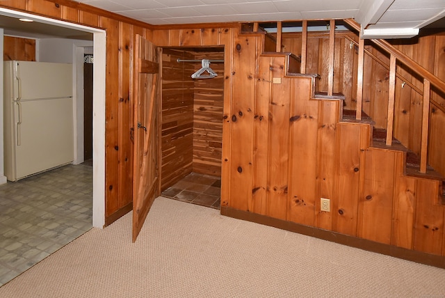 basement featuring white refrigerator and wood walls