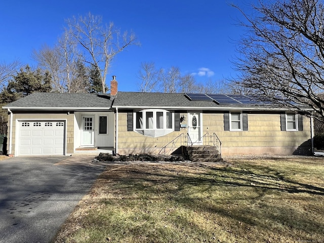 single story home with a front lawn, a garage, and solar panels