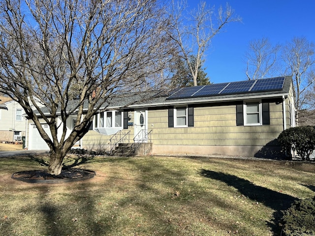 ranch-style home featuring a front lawn, solar panels, and a garage