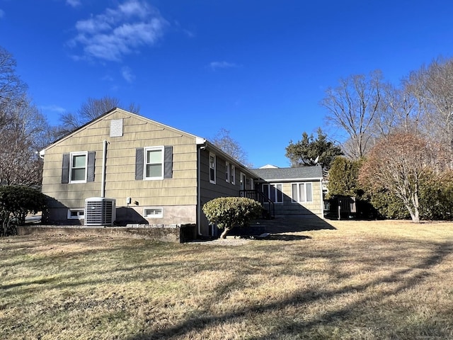 view of side of property featuring a lawn and central AC