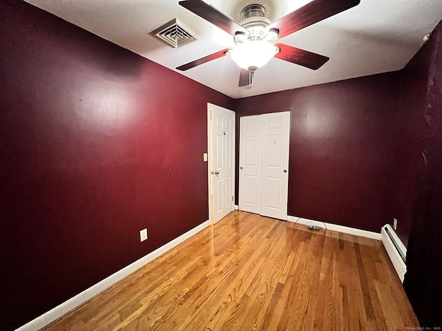 unfurnished room featuring light hardwood / wood-style floors, a baseboard radiator, and ceiling fan