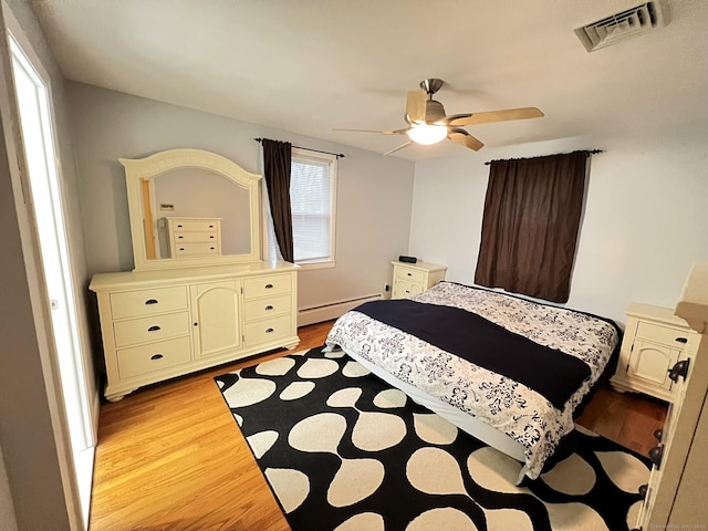 bedroom with ceiling fan, baseboard heating, and light hardwood / wood-style floors