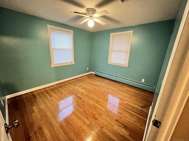 unfurnished room with ceiling fan, wood-type flooring, and a baseboard radiator