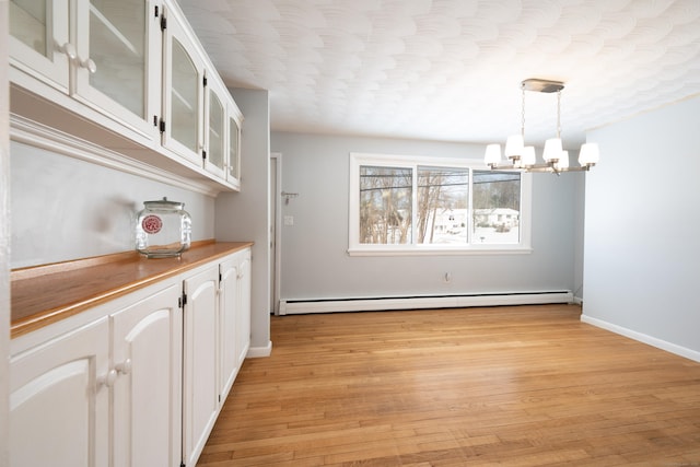 unfurnished dining area featuring a baseboard radiator, light hardwood / wood-style floors, a textured ceiling, and a notable chandelier