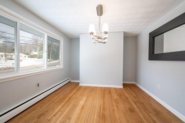 empty room featuring baseboard heating, light hardwood / wood-style flooring, and a notable chandelier