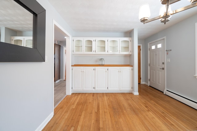 kitchen with a baseboard heating unit, white cabinets, a notable chandelier, and light wood-type flooring