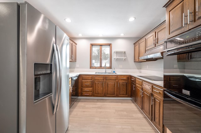 kitchen with sink, black appliances, and light hardwood / wood-style floors