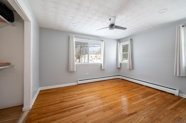 empty room with ceiling fan, light hardwood / wood-style flooring, and a baseboard heating unit