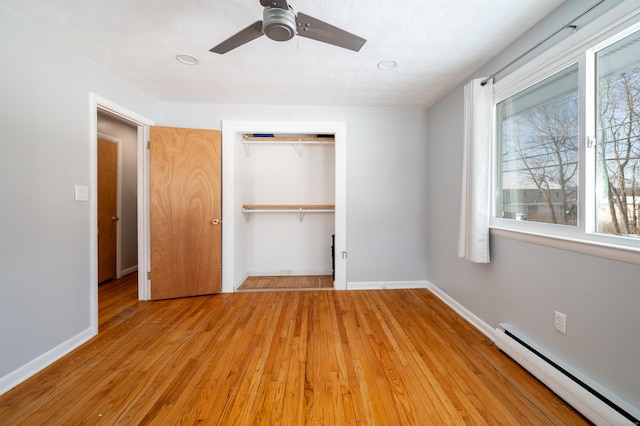 unfurnished bedroom featuring ceiling fan, baseboard heating, a closet, and light wood-type flooring