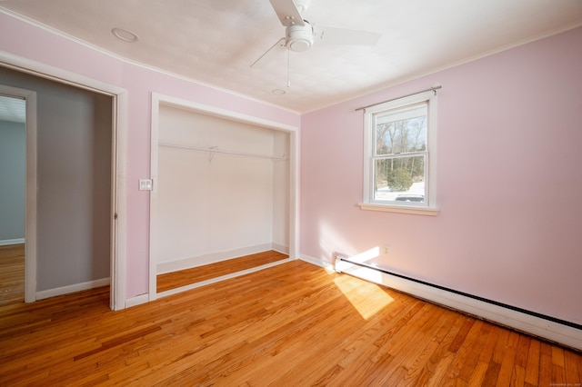 unfurnished bedroom featuring a closet, ceiling fan, light hardwood / wood-style flooring, and a baseboard heating unit