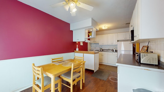 kitchen with white cabinetry, white refrigerator, backsplash, dark hardwood / wood-style floors, and stove