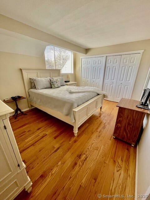 bedroom with light wood-style flooring, a textured ceiling, and multiple closets