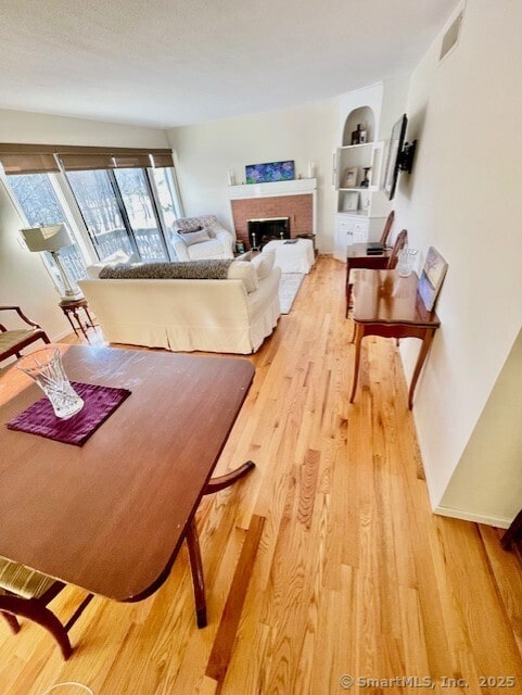 living area featuring a brick fireplace, baseboards, and wood finished floors