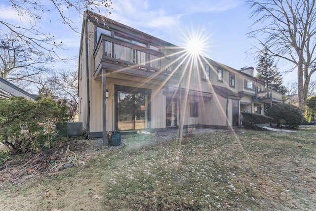 rear view of house featuring a balcony and a lawn