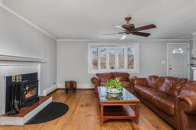 living room featuring wood-type flooring, baseboard heating, ceiling fan, and crown molding