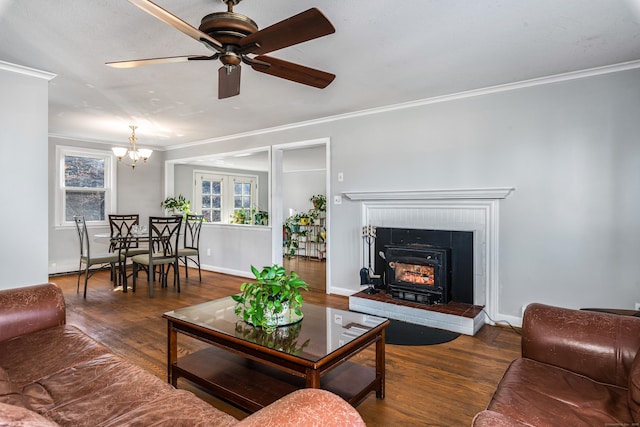 living room with ceiling fan with notable chandelier, dark wood-type flooring, crown molding, and a fireplace