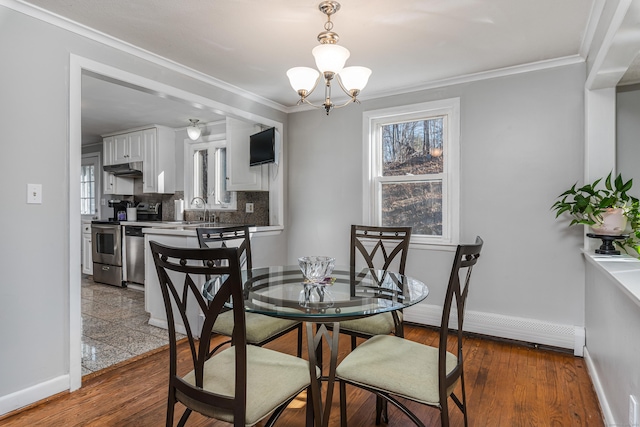 dining area featuring sink, a baseboard radiator, an inviting chandelier, and crown molding