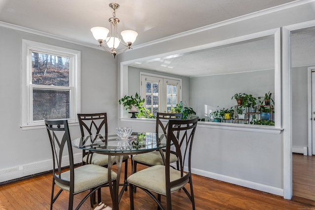 dining room with ornamental molding, a baseboard heating unit, a chandelier, and hardwood / wood-style flooring