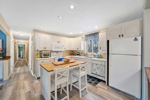 kitchen with tasteful backsplash, white cabinets, white appliances, and light hardwood / wood-style flooring