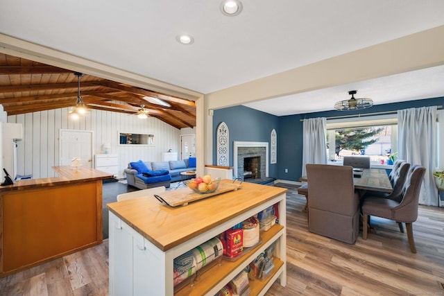 kitchen with white cabinets, wooden counters, a kitchen island, lofted ceiling with beams, and light hardwood / wood-style flooring