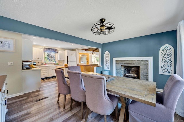 dining room featuring a fireplace, a textured ceiling, and light hardwood / wood-style flooring