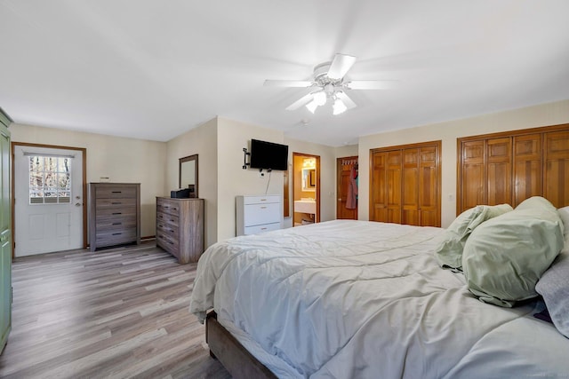 bedroom featuring light wood-type flooring, ceiling fan, two closets, and connected bathroom