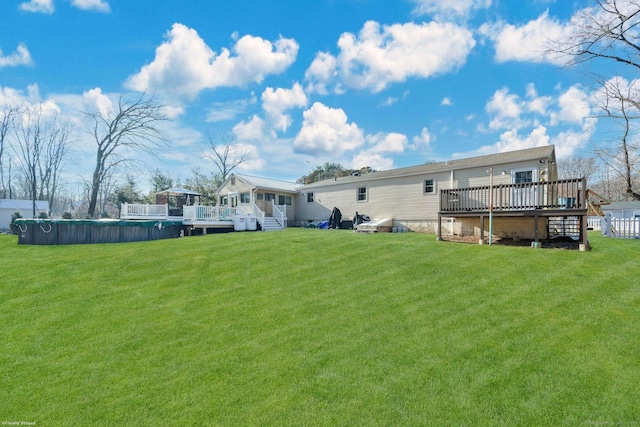 rear view of property featuring a pool side deck and a yard