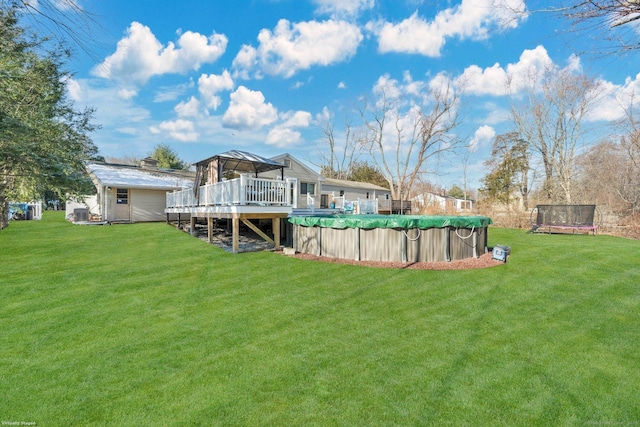 view of yard featuring a trampoline, a gazebo, and a swimming pool side deck