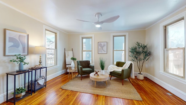 living area with crown molding, ceiling fan, and light hardwood / wood-style floors