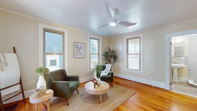 sitting room featuring wood-type flooring, ornamental molding, and ceiling fan