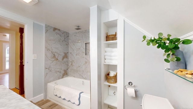 bathroom featuring tiled shower / bath combo, wood-type flooring, and toilet