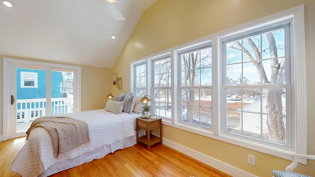 bedroom with access to exterior, vaulted ceiling, multiple windows, and light wood-type flooring