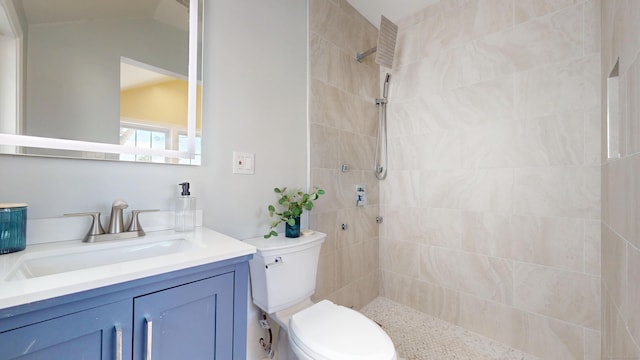 bathroom featuring vanity, lofted ceiling, tiled shower, and toilet