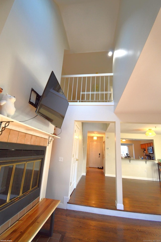 stairs with high vaulted ceiling, a tile fireplace, and hardwood / wood-style flooring