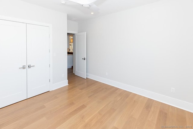 unfurnished bedroom with light wood-style flooring, baseboards, and a closet