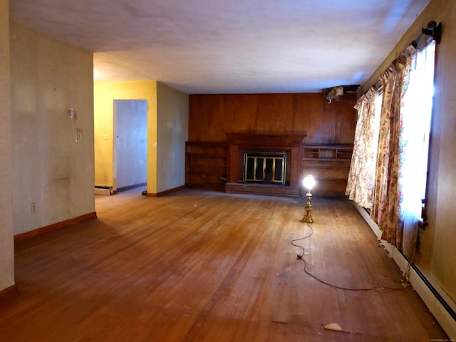 unfurnished living room featuring a fireplace, hardwood / wood-style flooring, and a baseboard radiator