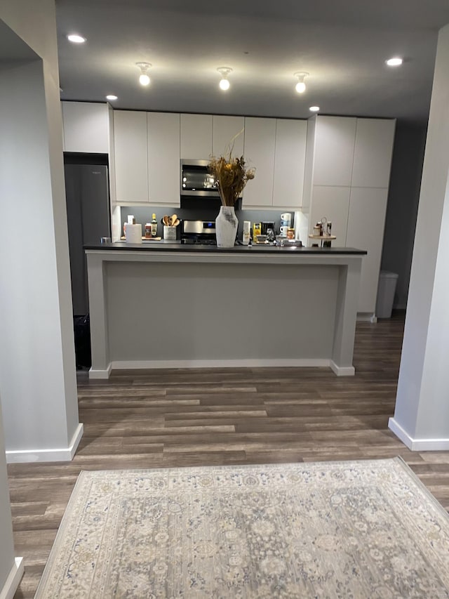 kitchen with white cabinets, dark hardwood / wood-style flooring, and stainless steel appliances