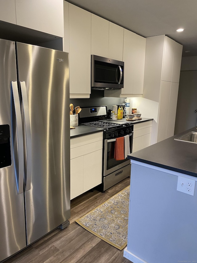 kitchen featuring sink, stainless steel appliances, white cabinetry, and dark hardwood / wood-style flooring