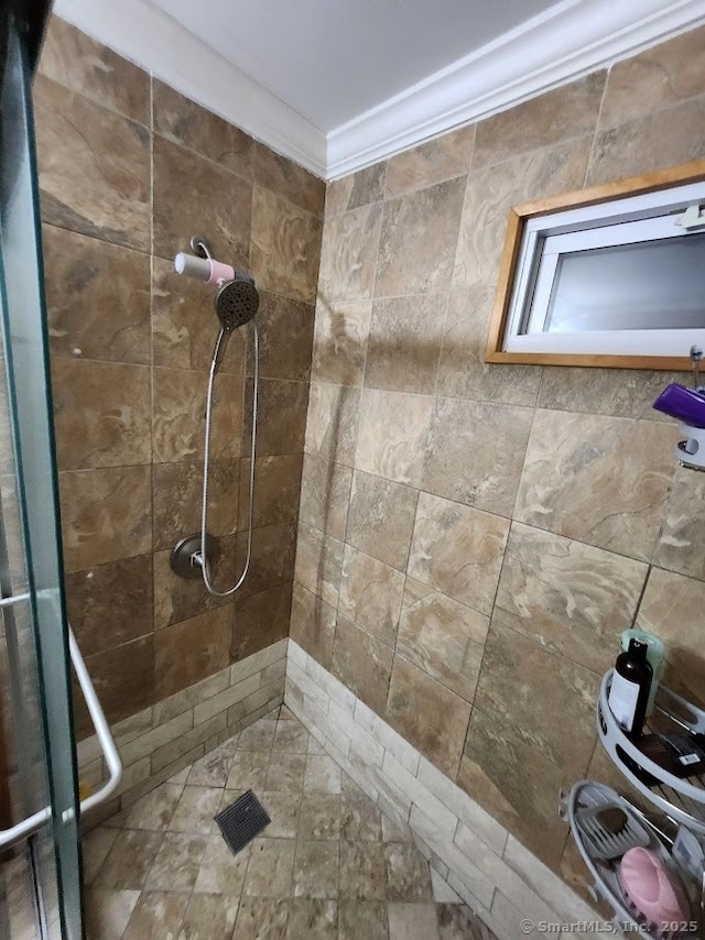 bathroom with ornamental molding and tiled shower