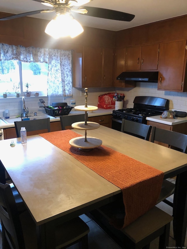 kitchen featuring ceiling fan, backsplash, black gas stove, a breakfast bar, and sink