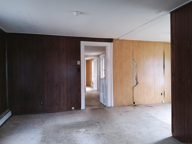 spare room with wood walls and a baseboard radiator