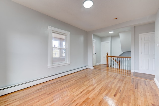 empty room with baseboard heating and light hardwood / wood-style floors