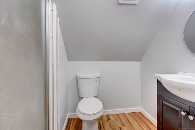 bathroom with hardwood / wood-style flooring, vanity, vaulted ceiling, and toilet