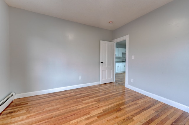 spare room featuring light wood-type flooring and baseboard heating