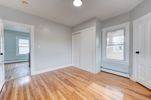 unfurnished bedroom with a baseboard radiator and light hardwood / wood-style flooring