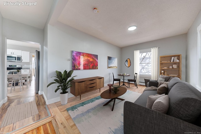 living room with baseboard heating, light hardwood / wood-style flooring, and a textured ceiling