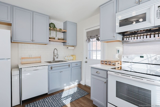 kitchen with white appliances, dark wood-type flooring, gray cabinets, backsplash, and sink