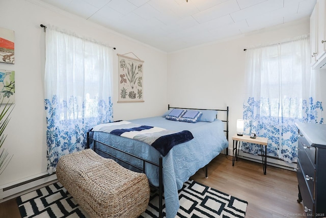 bedroom featuring a baseboard radiator, light wood-type flooring, and ornamental molding