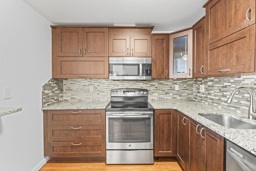 kitchen featuring sink, stainless steel appliances, light stone counters, and backsplash